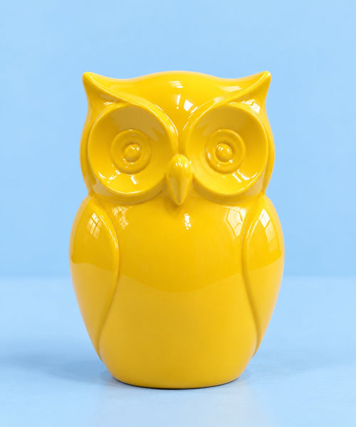 Glossy yellow Hoo’s Watching owl against a pastel blue studio background